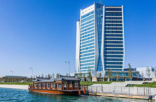 a boat in the water in front of a tall building at Silk Road by Minyoun in Samarkand