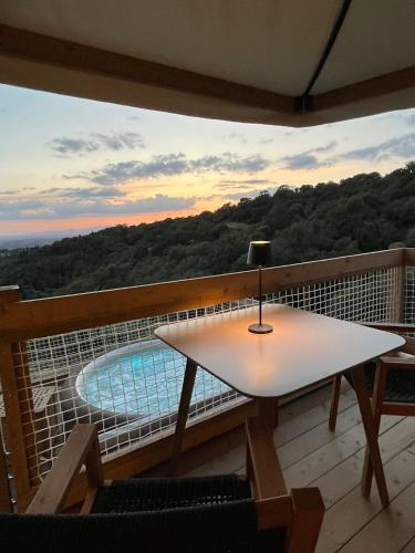 a table and chairs on a balcony with a pool at Glamping - Il Giardino di San Giorgio "Armida" in Montorgiali