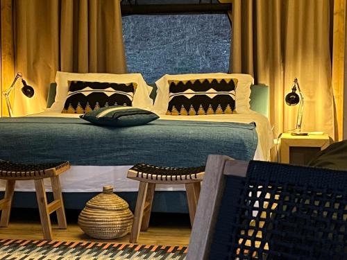 a bedroom with a bed with pillows and two chairs at Glamping - Il Giardino di San Giorgio in Montorgiali