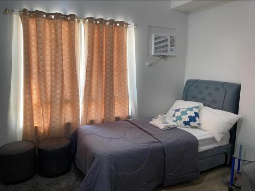 a bedroom with a bed and a window with curtains at MesaVirre Garden Residences Unit 402 in Bacolod