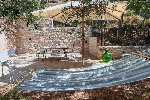 a hammock in a backyard with a table and a stone wall at L'Oasi nel Borgo in Monteroduni