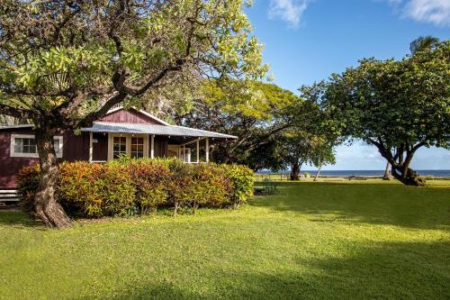 a house in a park with a tree and grass at Waimea Plantation Cottages, a Coast Resort in Waimea