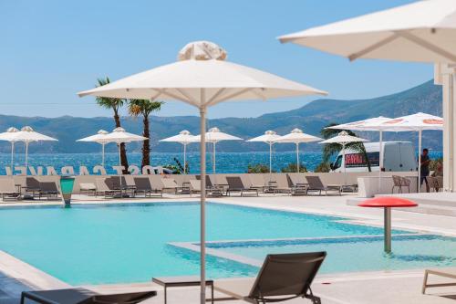 a swimming pool with chairs and umbrellas and the ocean at JOST Caravel in Vlorë