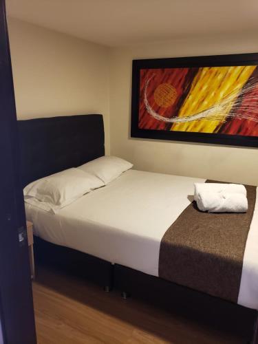 a bedroom with a bed and a painting on the wall at Hotel Casa Galeras in Pasto