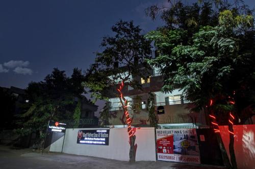 uma árvore em frente a um edifício com placas sobre ele em Townhouse OAK Red Velvet Suites & Inn Koregoan Park em Pune