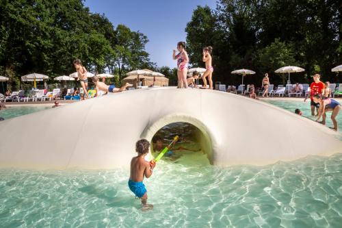 a boy playing on a water slide at a swimming pool at hu I Pini village in Fiano Romano