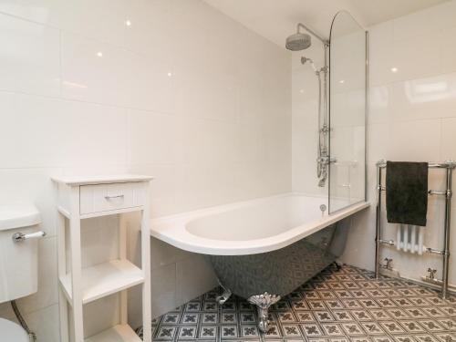 a white bathroom with a tub and a shower at Westgate Cottage in Lapford