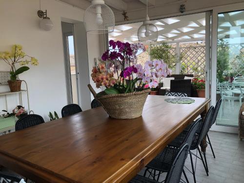 a dining room table with a basket of flowers on it at Attico Da Rosa con vista spettacolare a 360 gradi in Caltagirone