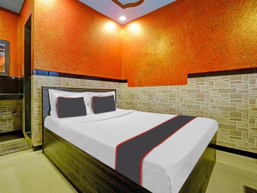1 dormitorio con 1 cama grande y pared de color naranja en Collection O Kinny Farmhouse And Resort en Dāndepāda