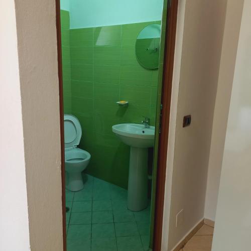 a green bathroom with a toilet and a sink at Hotel Eno in Përmet