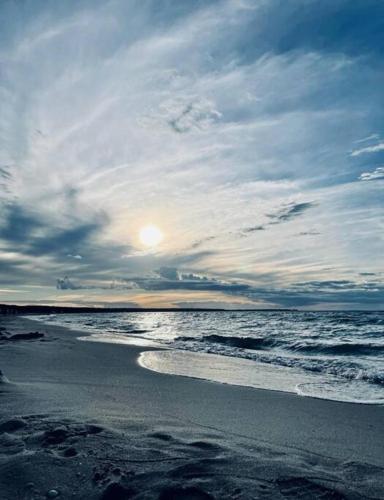 a beach with the sun setting on the ocean at Jules Heim mit Herz in Hanshagen