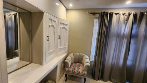 ein Badezimmer mit einem Waschbecken, einem Spiegel und einem Stuhl in der Unterkunft Green orchard skardu in Skardu