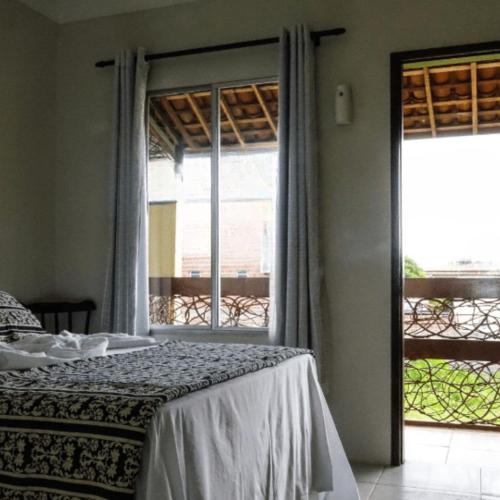 a bedroom with a bed and a large window at Happy Hotel Brisa do Mar in Ipojuca
