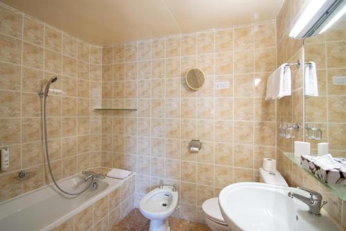 a bathroom with a tub and a sink and a toilet at Hôtel-Restaurant Le Lac in Malbuisson