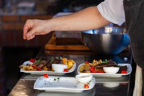 a chef preparing three plates of food on a counter at Grand Lakes Rooms in Plitvička Jezera