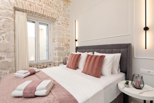 una camera da letto con un grande letto con cuscini bianchi e rosa di Modern-Vintage Old Town Suites a Città di Corfù