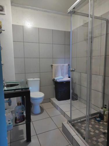 a bathroom with a toilet and a glass shower at Home far away from Home in Roodepoort