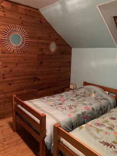 - une chambre avec 2 lits et un mur en bois dans l'établissement GITE EQUESTRE DE LA LANDE, à Bréhal