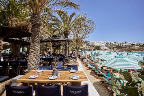 a restaurant with tables and chairs and palm trees at Nammos Hotel Mykonos in Psarou