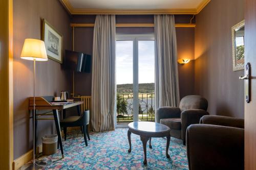 a hotel room with a desk and a living room at Hôtel-Restaurant Le Lac in Malbuisson