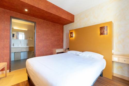 a bedroom with a large white bed and a bathroom at Hôtel-Restaurant Le Lac in Malbuisson