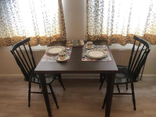 una mesa de comedor con 2 sillas y una mesa con platos. en Laaker Villa nearby outlet Roermond, en Ohé en Laak