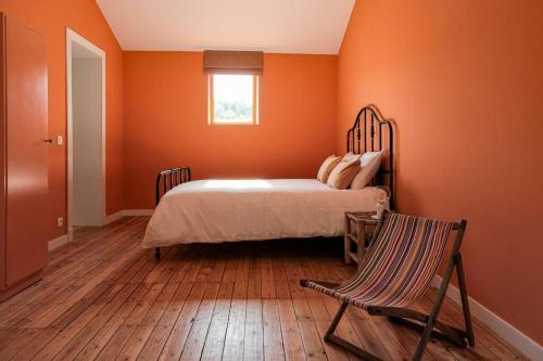 Schlafzimmer mit orangefarbenen Wänden, einem Bett und einem Stuhl in der Unterkunft La Maison du Rivage in Dinant