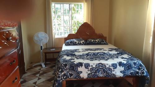 a bedroom with a blue and white bed and a window at Mango tree Oasis in Treasure Beach