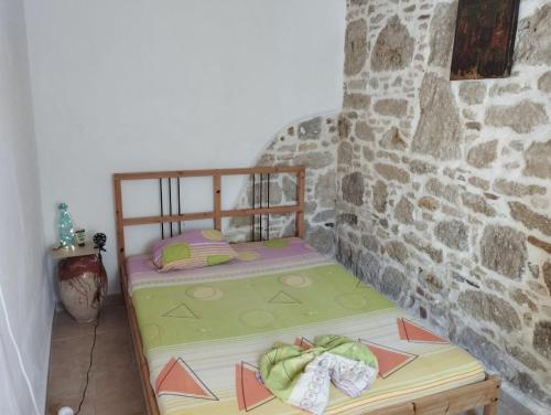 a small bed in a room with a stone wall at Artist Rooms - Triantafyllou Birth House in Kefalos