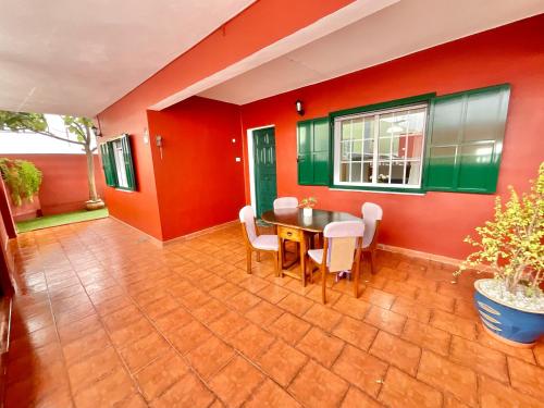 comedor con paredes rojas y verdes, mesa y sillas en Big&Confort ''con terraza y jardín'' en Tegueste