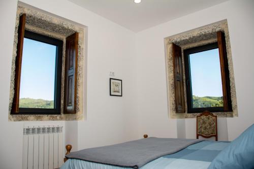 a bedroom with two windows and a bed at Quinta do Bairro in Vieira do Minho