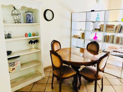uma sala de jantar com mesa e cadeiras e um relógio em Appartamenti Le Rondini em Cagliari