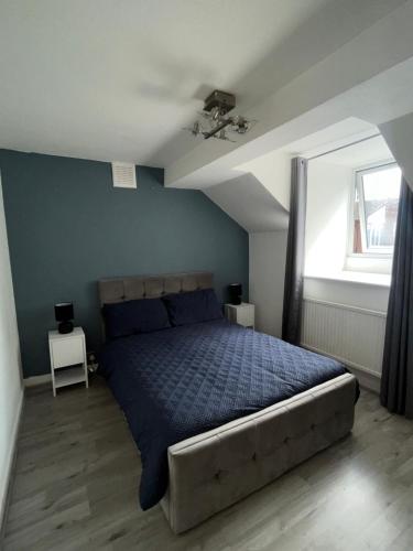 ein Schlafzimmer mit einem Bett mit blauer Decke und einem Fenster in der Unterkunft Lovely one bedroom apartment in Thornton Heath