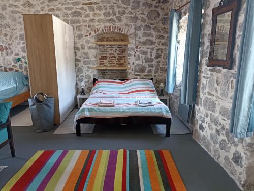 a bedroom with a bed in a stone wall at 19th century stone house on the seashore in Radovići
