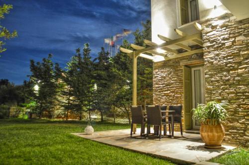 a patio with chairs and a table in a yard at Iro Suites in Andros