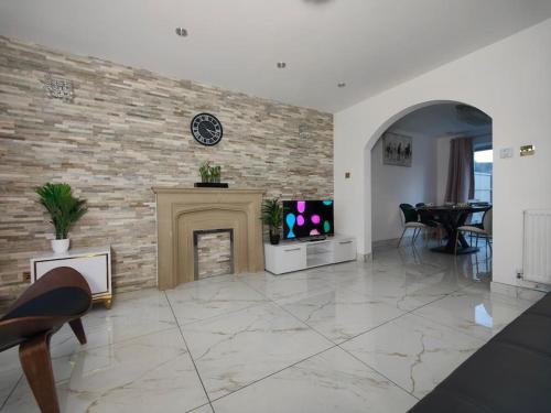 a living room with a fireplace and a clock on a brick wall at Tyburn Home, Birmingham with FREE Parking in Birmingham
