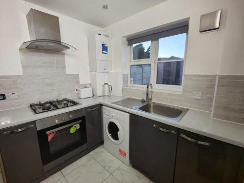 a kitchen with a sink and a washing machine at Tyburn Home, Birmingham with FREE Parking in Birmingham