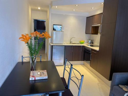 a kitchen with a table with a vase of flowers on it at Appartamento Costa adeje, Puerto colonn in Adeje