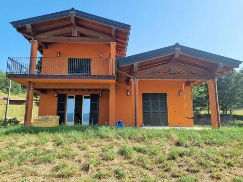 an orange house with a balcony on top of a field at Oasi di pace nella Val di Taro in Compiano