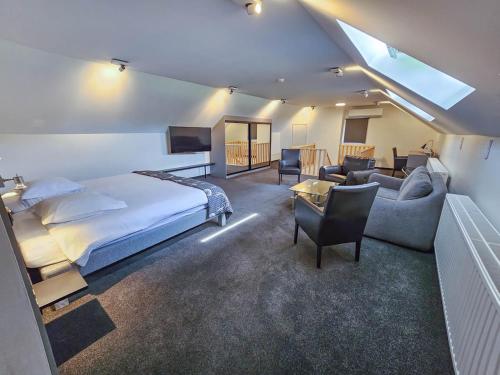 um quarto com uma cama e uma sala de estar com um sofá em Logis Hôtel Le Menobu em Theux