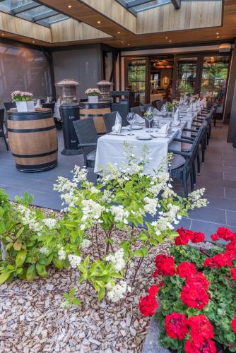 a restaurant with white tables and red flowers at Logis Hôtel Le Menobu in Theux