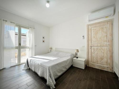 a white bedroom with a bed and a large window at Il Gioiello a Palau in Palau