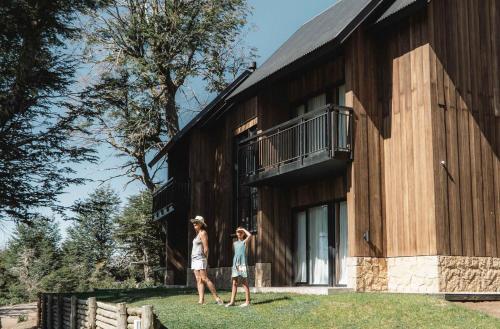 dos mujeres están de pie fuera de un edificio en El Refugio Ski & Summer Lodge en San Martín de los Andes