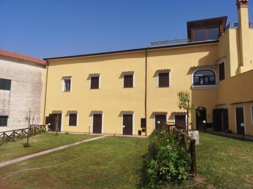 a large yellow building with windows and a yard at Casale Forno Vecchio in Tramonti