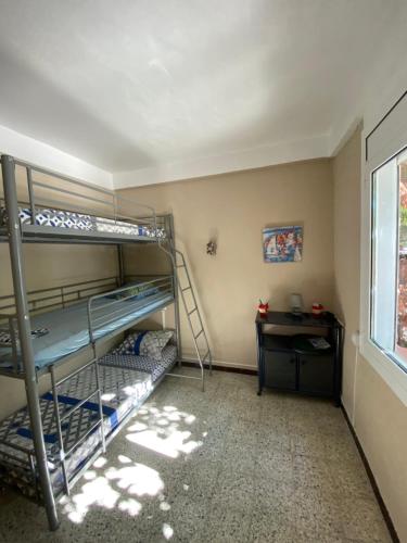 アルジェレス・シュル・メールにあるLes Ondinesの二段ベッド、デスク、窓が備わる客室です。