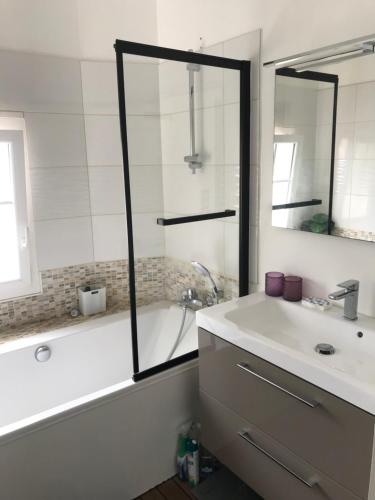 une salle de bain avec une baignoire, un lavabo et un miroir dans l'établissement Pavillon 50 m² avec terrasse, à Châtelaillon-Plage