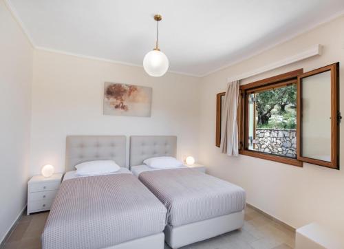 two beds in a white room with a window at Kyknos by Vintage Travel in Meganisi