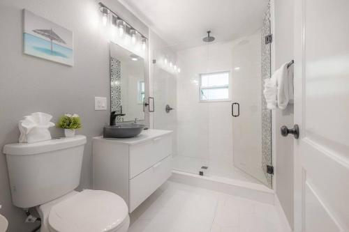 a white bathroom with a toilet and a shower at The Pearl Cottage 2b/1R with King and FAST WIFI in Tampa