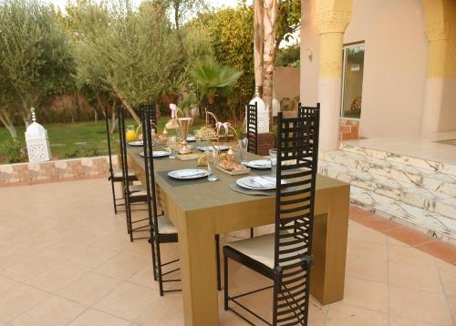 a long table with chairs and food on it at Villa Paradis in Marrakech