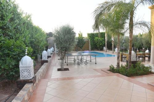 a patio with a table and chairs next to a pool at Villa Paradis in Marrakech